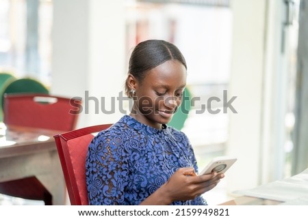 image of beautiful african lady holding a smartphone in a cafeteria
