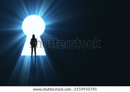 Backlit man in hoodie standing in bright keyhole opening on dark background with mock up place and light rays. Dream, future and opportunity concept