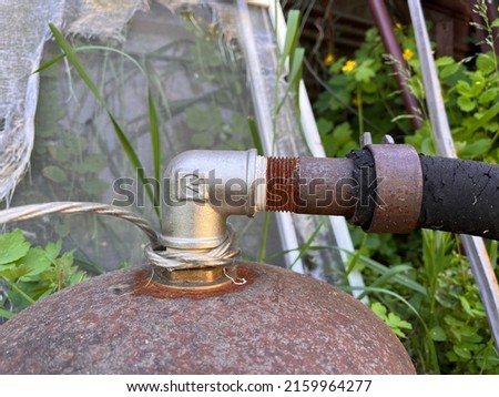 Closeup of a new metal faucet (valve) installed on a rusty vessel to connect flexible pipe. Connection of valve and old pipe with rusty thread. Rusty iron against blurry background Royalty-Free Stock Photo #2159964277
