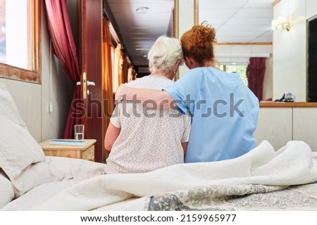 Nurse hugs elderly woman sitting on bed in hospice for comfort Royalty-Free Stock Photo #2159965977