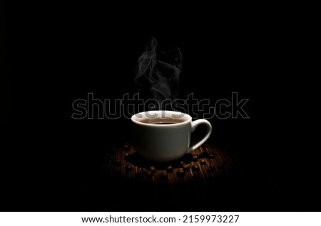 A cup of coffee with steam on a wooden table, scattered coffee beans.Light from above.Dark scene. banner space layout for adding text.