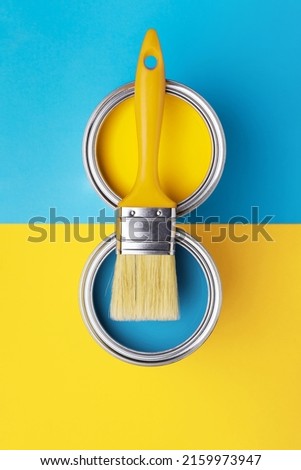 Can of yellow paint with brush on yellow and blue background. Top view, redecorating in ukrainian flag colors. Royalty-Free Stock Photo #2159973947
