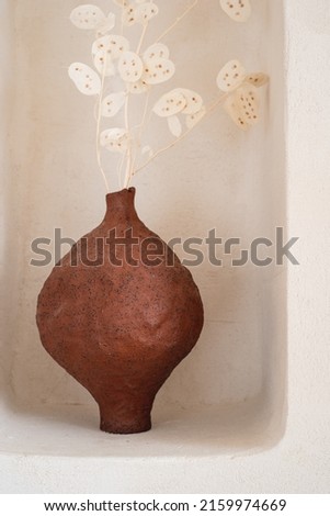 Ceramic handmade vase in a minimalist style on a shelf in the wall.