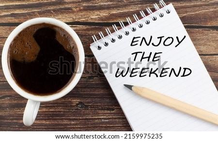 ENJOY THE WEEKEND text on a notebook with coffee on wooden background