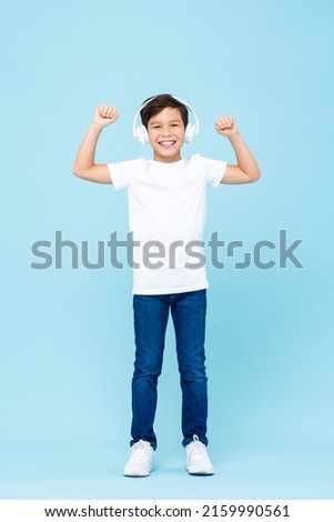Young cute mixed race boy wearing headphones listening to music and smiling in isolated studio light blue color background