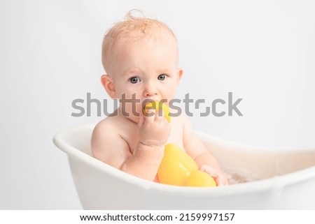 child boy bathes in white bath with foam and ducks