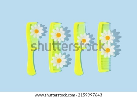 Spring creative pattern with neon yellow hair combs and white flower heads on pastel blue background. 80s or 90s aesthetic fashion bloom concept. Minimal romantic summer idea with.