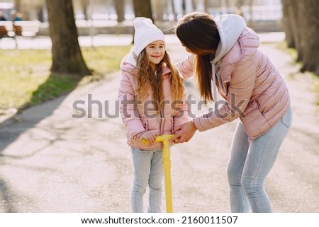 Mother with daughter in a spring park with skate