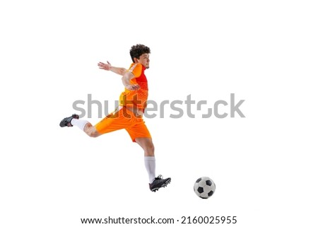Leg kick. Professional football, soccer player in motion isolated on white studio background. Concept of sport, match, ad, active lifestyle, goal and hobby. Sportsmen wearing bright orange football