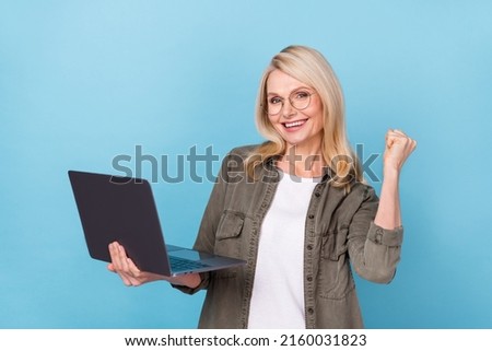 Photo of excited middle aged lady boss use netbook fist up lucky finance income isolated blue color background