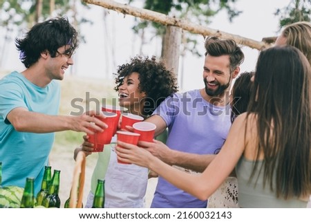 Photo of cheerful positive people hold plastic bear cups have fun enjoy free time outdoors