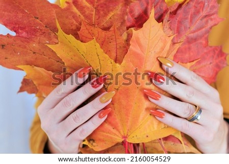Female beautiful hands with long nails and a yellow orange nail polish