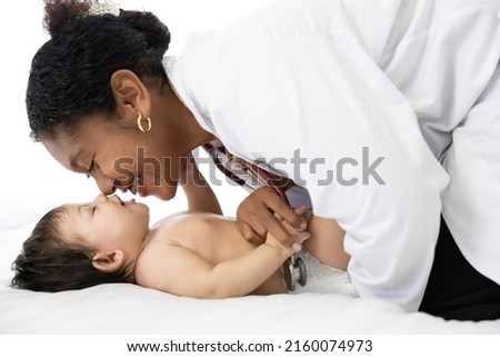 African doctor pediatrician examining and kissing baby on the bed