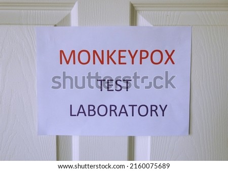 'Monkeypox Test Laboratory' wording on A4 paper stuck to white wooden door. 