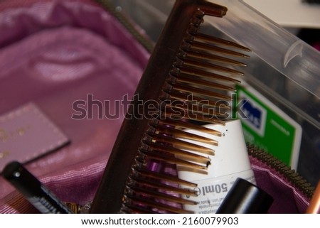 In the foreground a broken brown comb inside a makeup holder.
