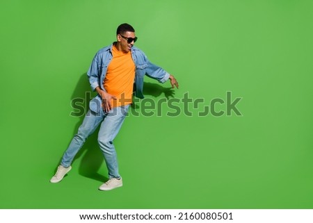 Full length image of good mood young male in sunglass dancing in nightclub isolated on green color background