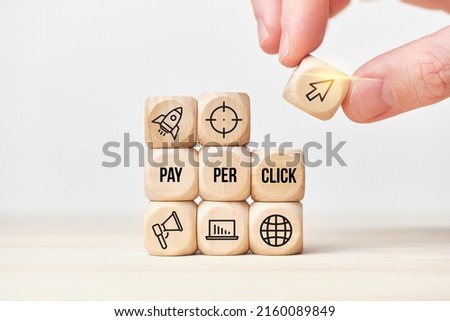 Concept Pay per click or PPC. Person stacks wooden cubes from text and icons Royalty-Free Stock Photo #2160089849