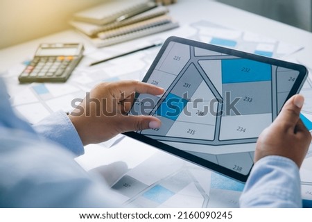 Man holding a tablet looking at lots of lands. Land plot management - real estate concept with vacant land for building construction and housing subdivision for sale, rent, buy, or investment Royalty-Free Stock Photo #2160090245