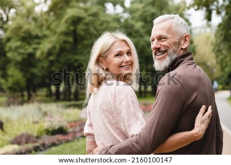 Smiling happy caucasian mature spouses hugging embracing while walking on a date in park together. Bonding, love and relationship Royalty-Free Stock Photo #2160100147