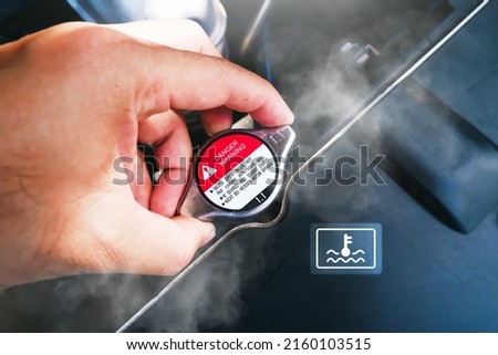 The mechanic hand was holding onto the car hot radiator cap with  the water smoke of the radiator spread around,car temperature icon Royalty-Free Stock Photo #2160103515