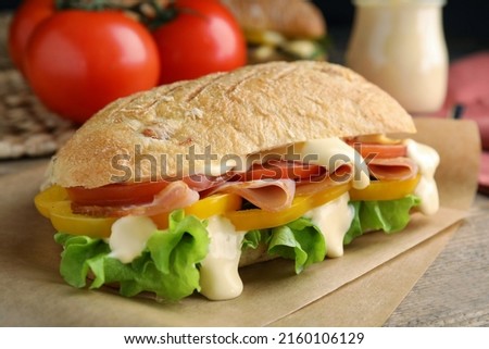 Delicious sandwich with vegetables, ham and mayonnaise served on wooden table, closeup Royalty-Free Stock Photo #2160106129