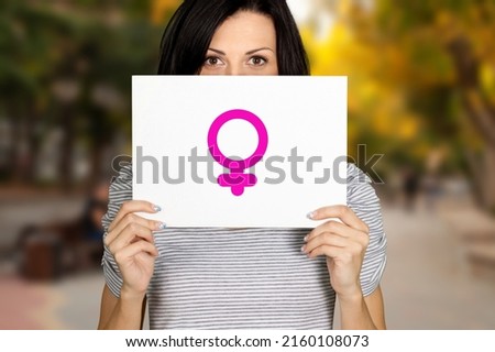 Woman holding white cardboard sign with symbol. Feminist concept activism