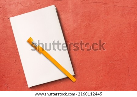 Notepad for writing text with pen on a red background.
