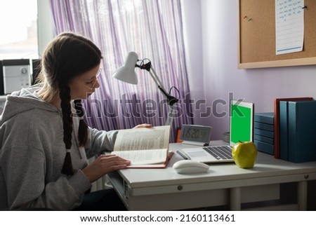 Green screen. A student with braids and glasses at home is reading a book.