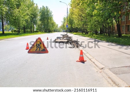 Construction road sign and orange traffic cones. Preparation for laying new asphalt pavement. Road repair and rodework concept. Traffic cones on a street as a warning sign.