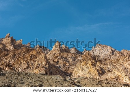 Scenic mountain landscape with sharp rocks under blue sky in sunny day. Colorful scenery with gold sunlit sharp rocky mountains. Sharp rocks in bright sun. High rocky mountains in golden sunlight. Royalty-Free Stock Photo #2160117627