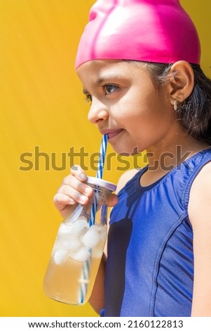 Cute little girl in a swimsuit sunbathing, while having a lemonade