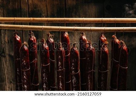 Process of smoking sausage hang in a cupboard with smoke. Clouds of smoke rise up and envelop the sausages hanging in a row.