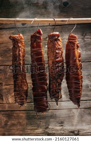 Traditional method of smoking meat in smoke. Smoked ham, bacon, pork neck and sausages in a smokehouse.