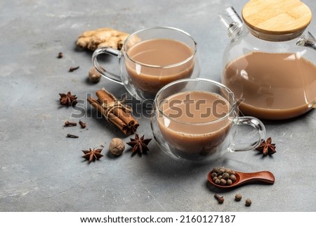 Glass cup of traditional indian masala chai tea with milk and spices on gray background. banner, menu, recipe place for text, top view.