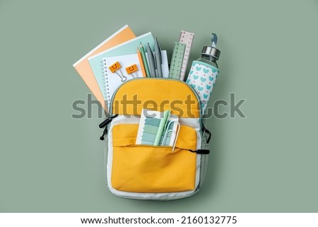 Opened School backpack with stationery  on green background. Concept back to school. School supplies. Royalty-Free Stock Photo #2160132775