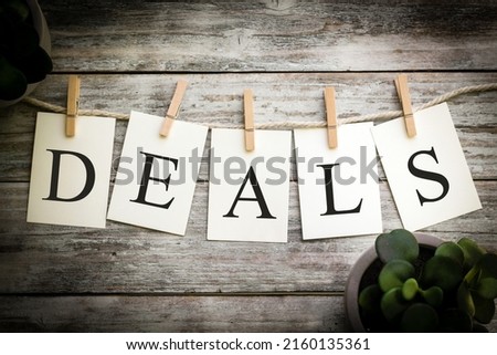 A set of printed cards spelling the word DEALS on an aged wooden background.