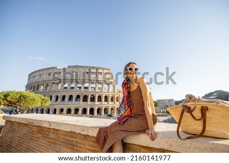 Portrait of a cheerful woman on background of Coliseum in Rome on a summer time. Concept of visiting famous landmarks and travel Italy. Girl wearing dress and colorful shawl Royalty-Free Stock Photo #2160141977