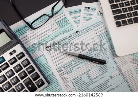 US tax form 1040 with pen laptop and glasses on black