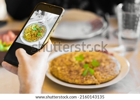 A hand taking a picture to a quinoa pie healthy food with a smartphone at restaurant.