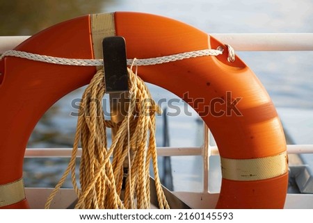 Safety lifeguard with rope. A red lifebuoy on white background. A detail of vintage resque equipment. Vintage old life buoy and hawser on a sailboat. Royalty-Free Stock Photo #2160145593