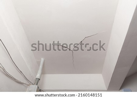 Crack in the ceiling. Surface paint and stucco are damaged. Hack repair, poor painting of ceiling in the entrance. Bad plaster. Royalty-Free Stock Photo #2160148151