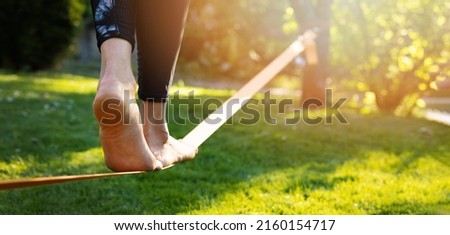 person walking on a slackline barefoot. strength and balance exercises Royalty-Free Stock Photo #2160154717
