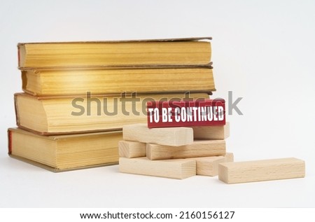 Education concept. On a white surface, a stack of books and wooden blocks, on a red block there is an inscription - TO BE CONTINUED