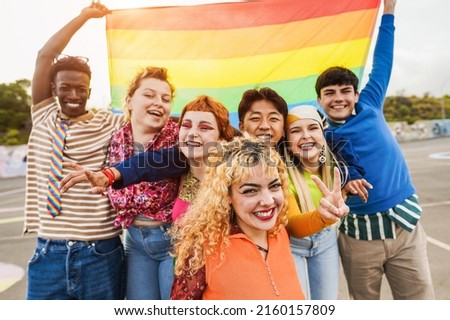 Young diverse people having fun holding LGBT rainbow flag outdoor - Focus on center blond girl Royalty-Free Stock Photo #2160157809