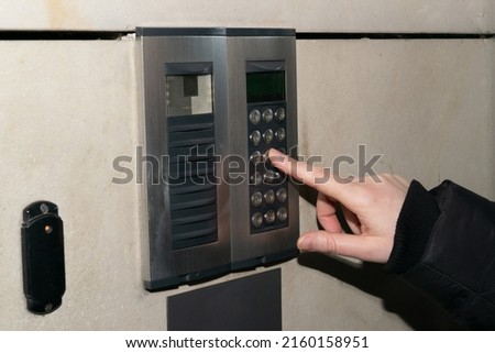 Secure home system. Hand pressing on intercom keypad, using door phone, doorphone, entryphone, videophone call Royalty-Free Stock Photo #2160158951