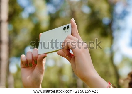 Close up view of young woman hands taking horizontal photo with her smart phone.
