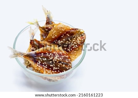 Dried fish with sesame seeds on white background.