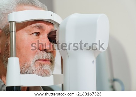 examination of the elderly man on the corneal topographer. Videokeratograph is medical device for determining curvature of cornea. mandatory device for modern clinic or opticians shop. Royalty-Free Stock Photo #2160167323
