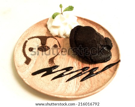 molten lava chocolate cake with whipping cream and cute penguin cartoon from coco powder as decoration on wooden dish