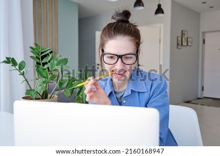 Photo of lady sit desk look screen laptop hold pen write notepad wear spectacles white sweater in living room home indoors.